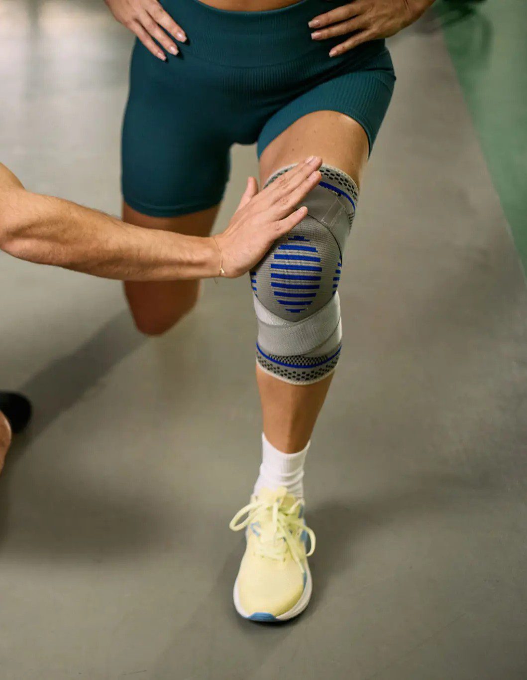 Person wearing a knee brace and athletic shoes.