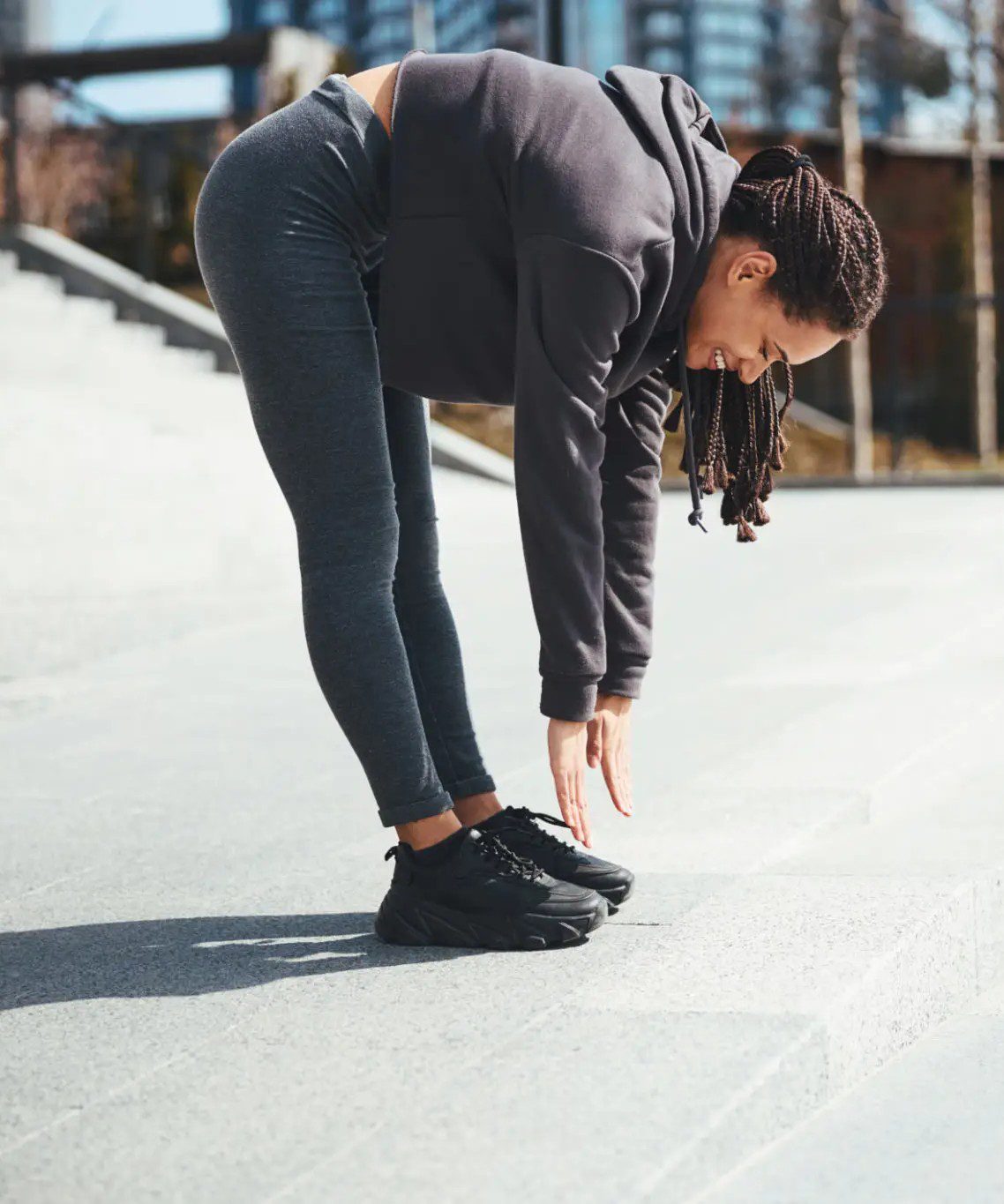 Woman stretching and touching her toes outdoors in workout clothes.